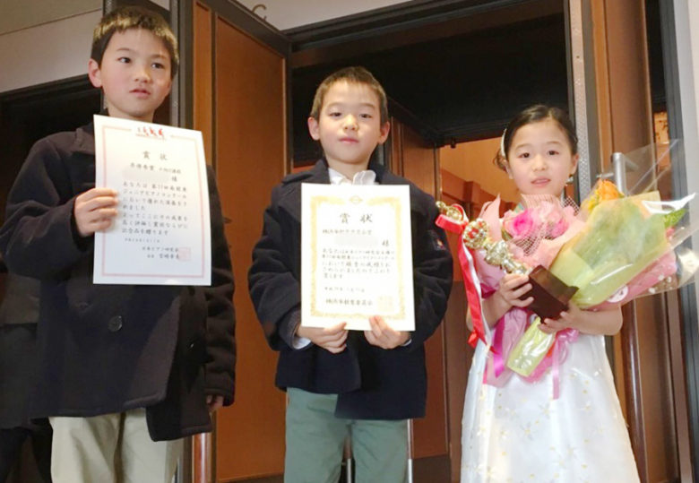 賞状を持った男の子2名と、トロフィーと花束を持った女の子の写真